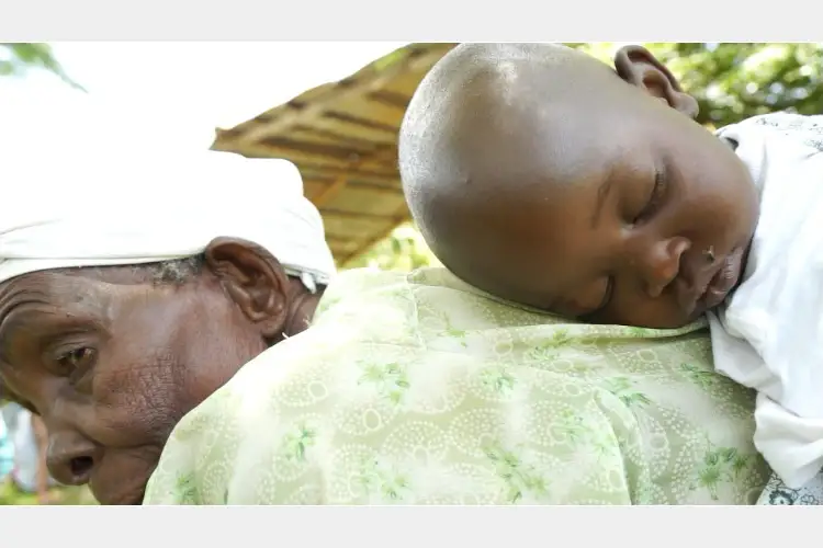 A baby asleep on their grandmother's back A baby asleep on their grandmother's back