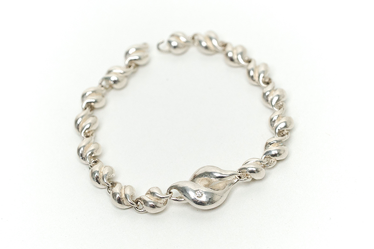 A silver bracelet with tiny seashells on the chain and a big seashell with a small diamond in the middle.