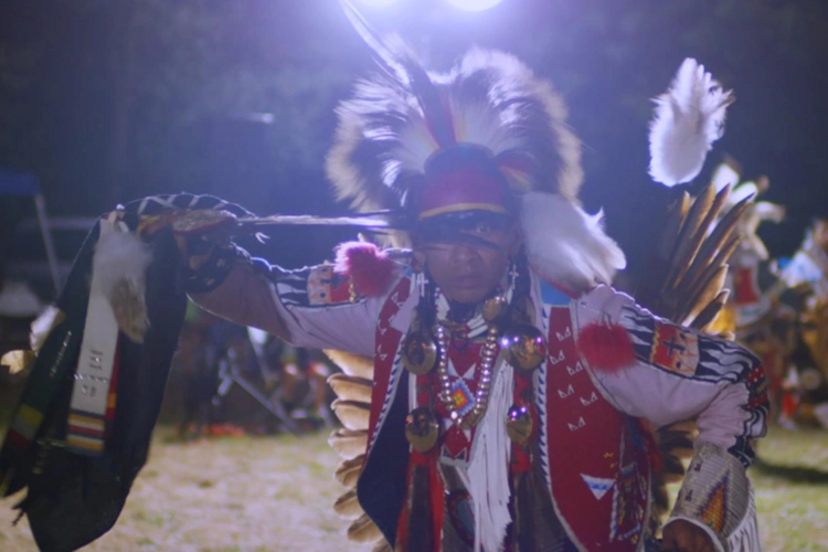 An Indigenous man wearing regalia dances. 