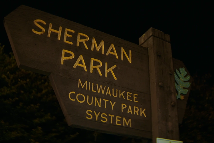 A brown sign with dark yellow letters: "Sherman Park; Milwaukee County Park System." 