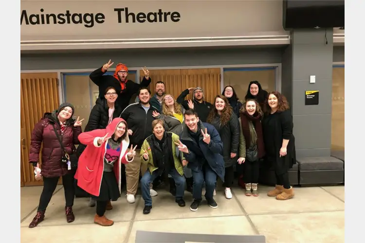 A group of students posing in front of the doors to a theater. A group of students posing in front of the doors to a theater.