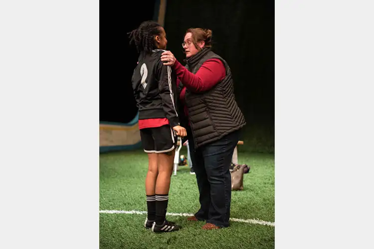 Coach speaks face-to-face with a young athlete on indoor turf.