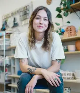 Headshot of Karly Jean Kainz kneeling in a studio space.