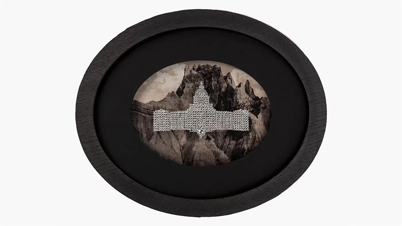 An oval shaped artwork featuring a capitol style building overlaid onto a mountain landscape.