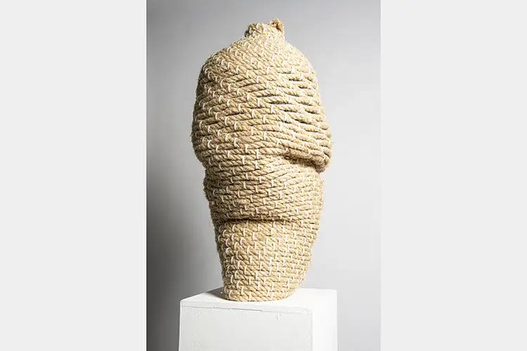 sprouts woven up and down along a sculpture made of rope resembling a tall basket sprouts woven up and down along a sculpture made of rope resembling a tall basket