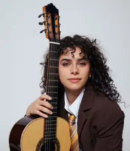 Headshot of Leonela Alejandro holding a guitar.