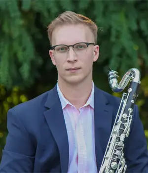 Headshot of Besnik Abrashi outdoors with a clarinet.