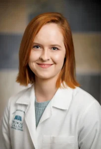 A person in a lab coat smiling at the camera.