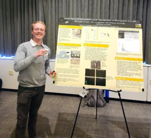 A person stands next to a poster display showing research.
