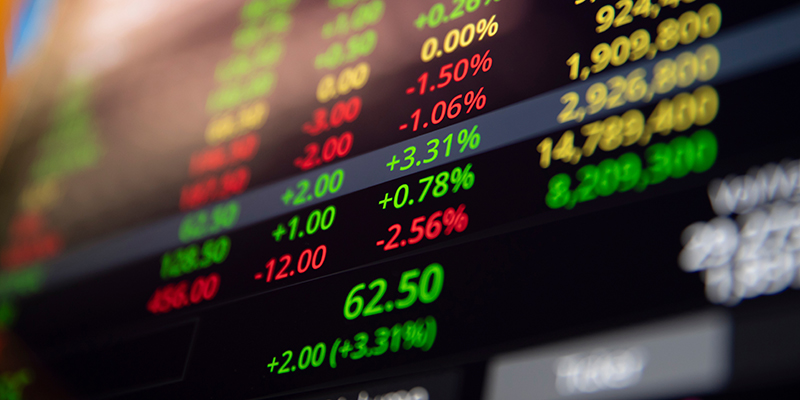 A stock market ticker screen displaying price changes and percentages in red and green numbers against a dark background.