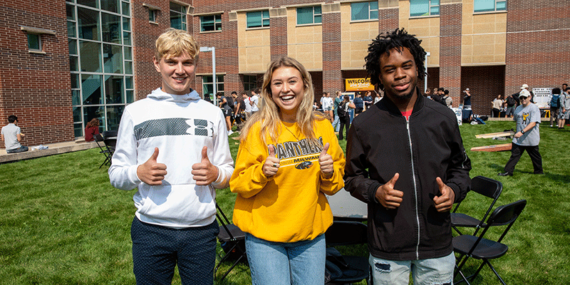 Julia and 2 students thumbs up at picnic