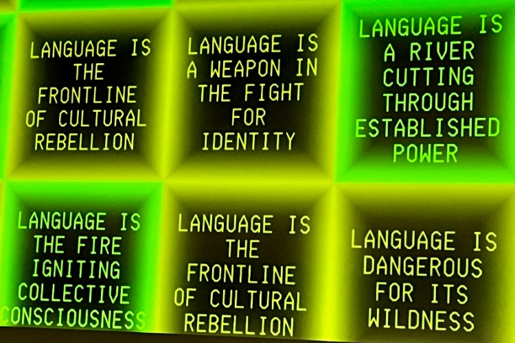 Poetry generated by Sasha Stiles during the Language as Collaborator: Co-Creating with Thinking Machines workshop, part of C21's Aesthetics, Art, & AI program series. Phrases such as "language is the frontline of cultural rebellion" appear inside the squares of a grid projected onto a all.