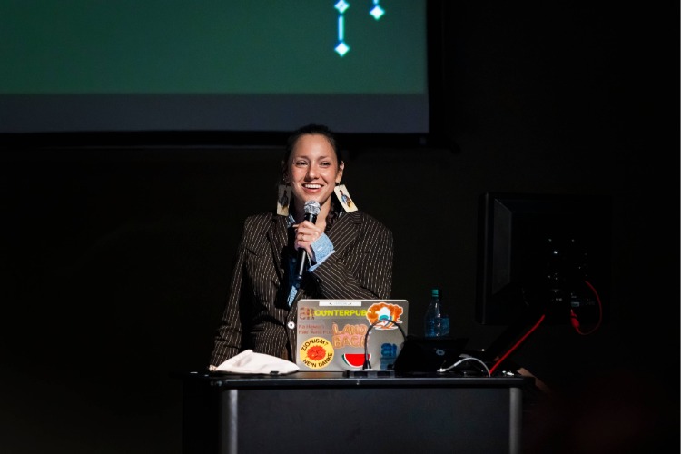 The artist Kite laughs into a handheld microphone during the Q&A for her artist talk, part of C21's Aesthetics, Art, & AI program series. The artist Kite laughs into a handheld microphone during the Q&A for her artist talk, part of C21's Aesthetics, Art, & AI program series.