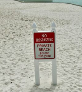 Sign on a beach that says "No Tresspassing, Private Beach"