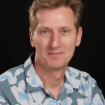 a white person in a floral shirt looks at the camera