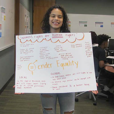Smiling student holding a poster about gender equality