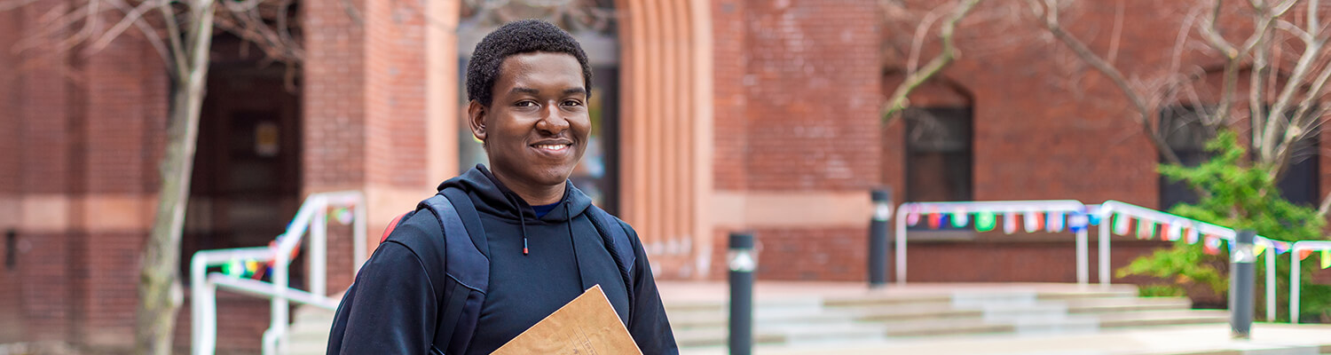 Nigerian student smiling in front of red brick building