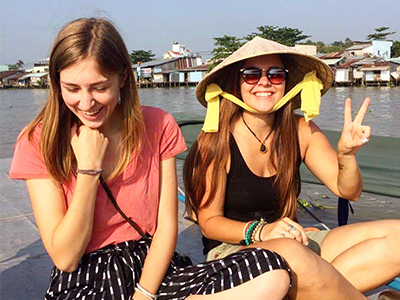 Two smiling female students sitting in front of water
