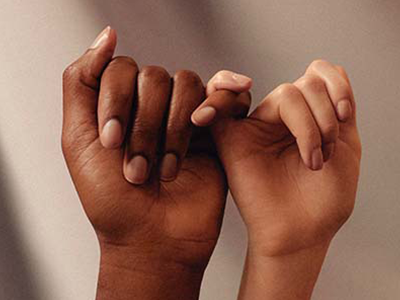 African American hand and White hand holding pinkies