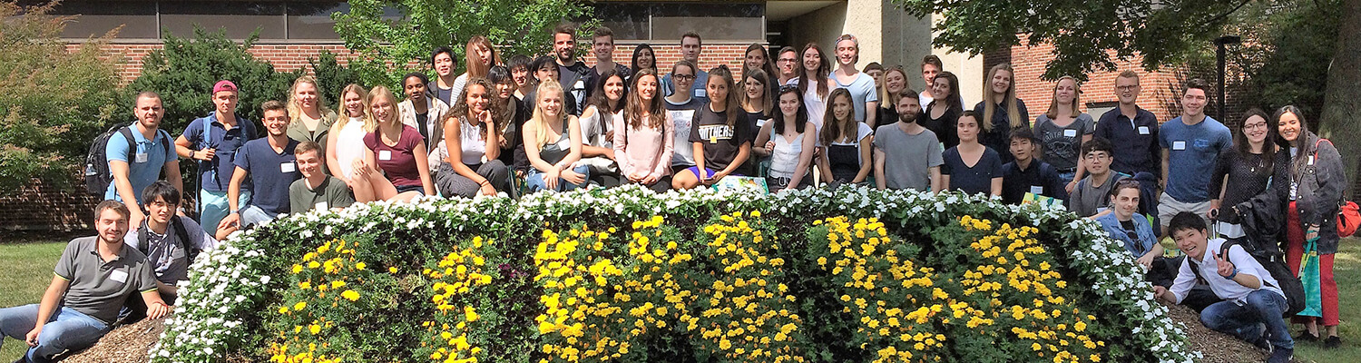 Group of UWM exchange students gathered in front of flowers