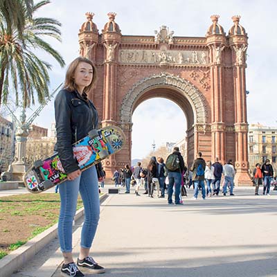Female student with skateboard in front of landmark