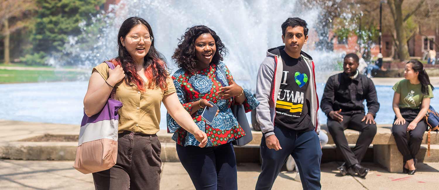 Diverse group of international students walking in front of the UWM Fountain together
