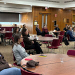 WWHEL members sitting in groups at multiple circle tables. All members are listening intently and are enjoying themselves.