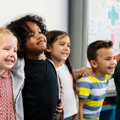 Group of diverse children smiling in classroom.