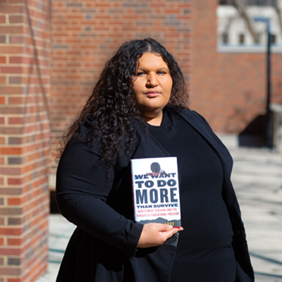 Researcher (Black woman) holding her book about preparing teachers to talk about race and racism in schools.