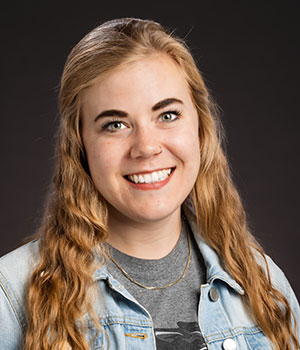Front-facing portrait of Michaela Kaiser, smiling, with shoulders partially visible.
