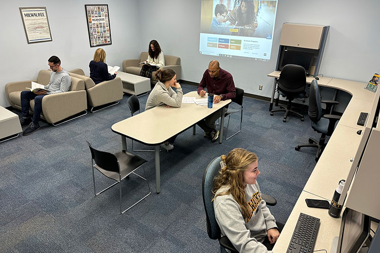 Lounge space with comfortable furniture, computers and a projector.