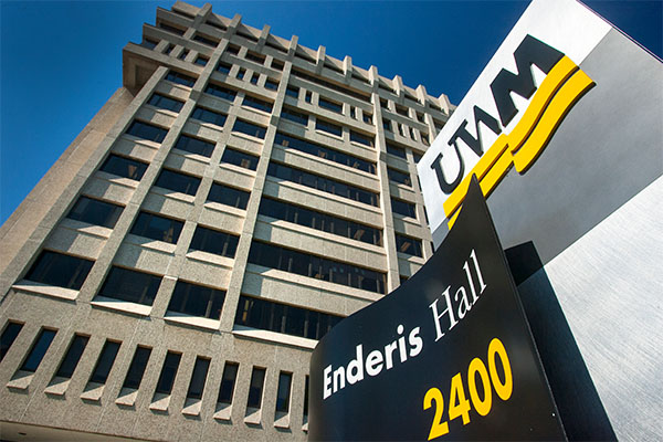 View of Enderis Hall looking up at the building from below with a black and gold UWM sign in front.