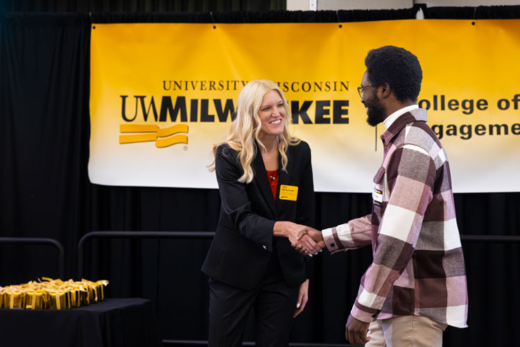 College of Community Engagement and Professions Dean Tina Freiburger smiling and shaking hands with graduate walking across stage