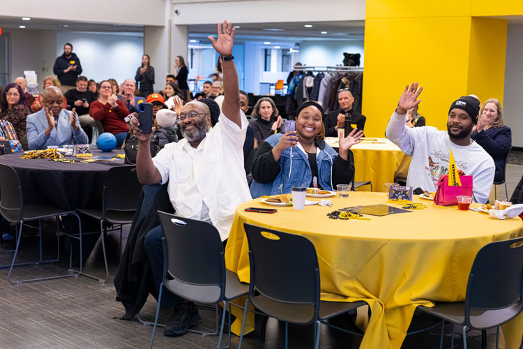 Celebratory families sitting at circular tables who are waving and clapping