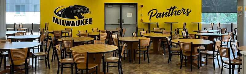 A seating area featuring tables, chairs with decals on the wall that read "Panthers"