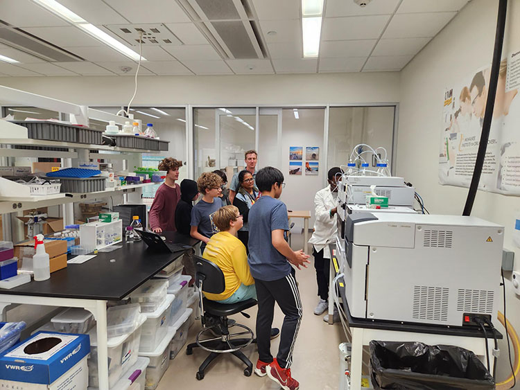 Students gathered around a mass spectrometer during a laboratory demonstration
