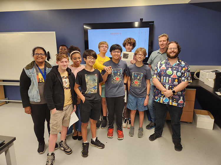 Group of middle school students and instructors posing in a chemistry laboratory