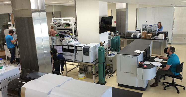 Researchers working with analytical instruments including mass spectrometers in a modern laboratory"
