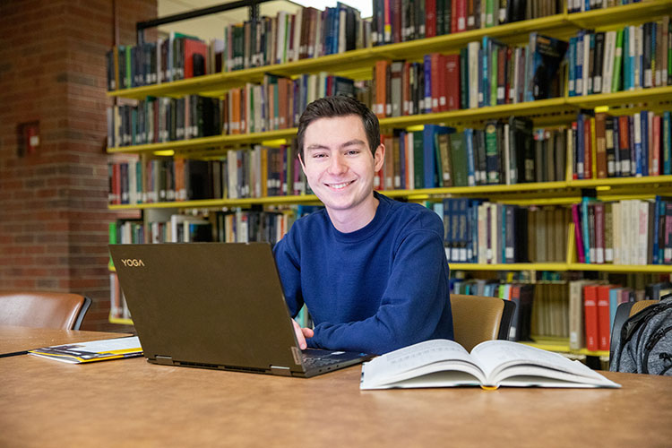 First year student Daniel Miller (white man) studying in the campus library