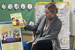 School of Education December 2022 graduate Addison Sagat displaying a book for students in her classroom