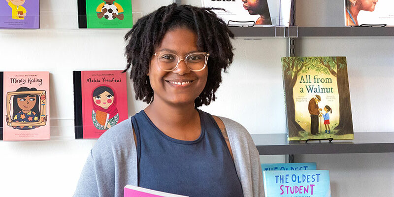 School of Education alumna Ashley Valentine, poses for a picture inside of her bookstore and tutoring center named Rooted MKE