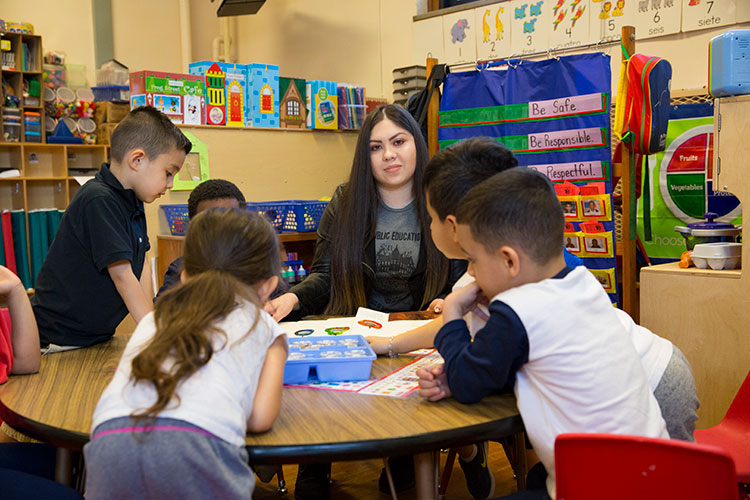 Young teacher (Hispanic woman) working with a group of young children