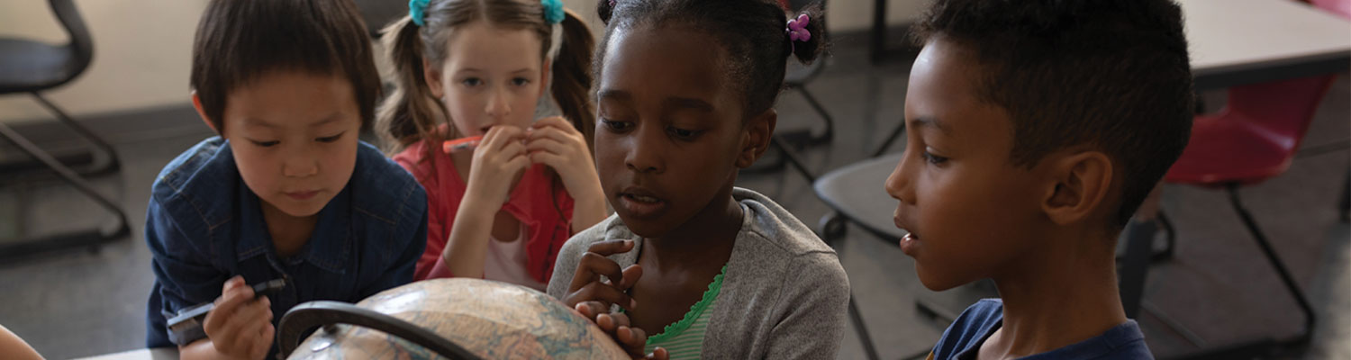 School children of diverse backgrounds looking at a globe.