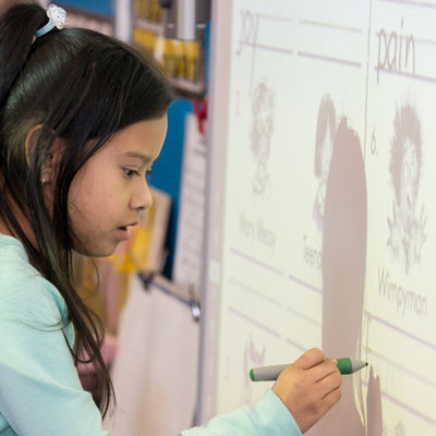 Young female student writing on a Smart Board.