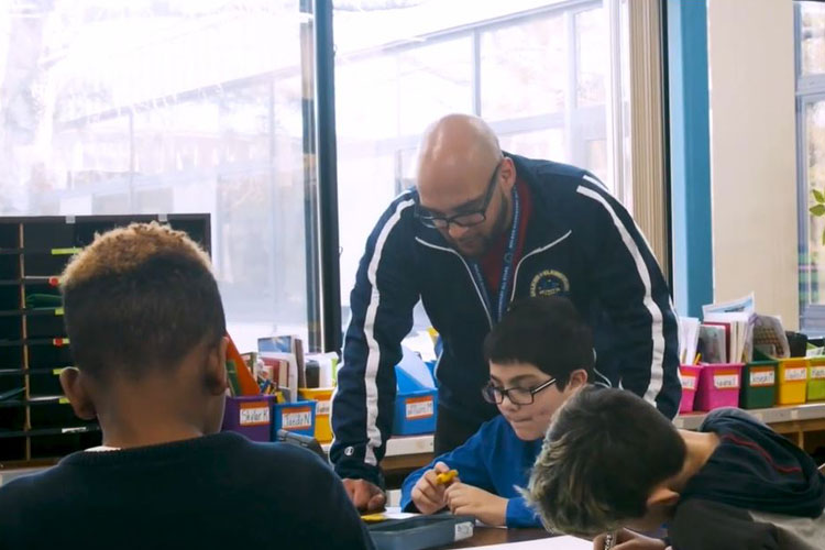 Male teacher helping students in the classroom.