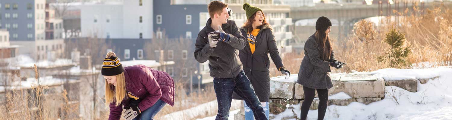 One male and three female students having fun throwing snowballs in Milwaukee