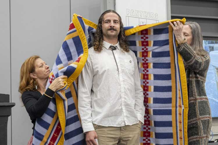 Michael Claus Thiel, UWM Alumni, receiving blanket after their keynote. 