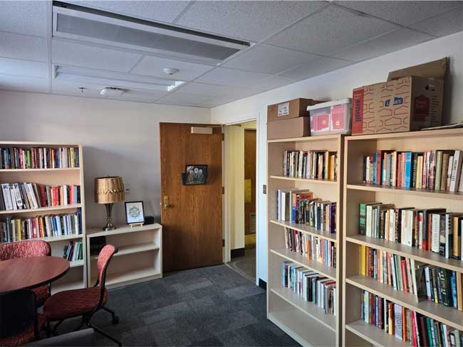 Library with three bookshelves, open door, and table with chairs.
