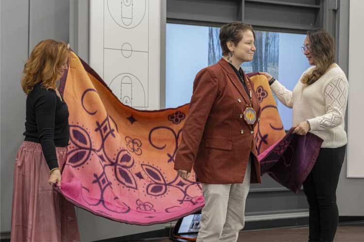 Steph Fones, UWM Alumni, receiving blanket after their keynote. 