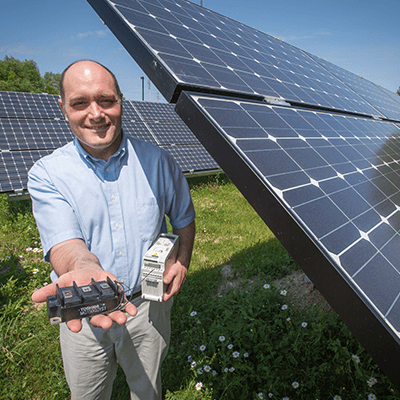 Rob Cuzner stands next to solar panels